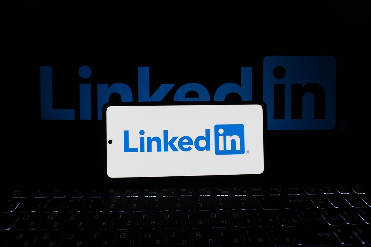 services-04 Smartphone affichant le logo LinkedIn avec clavier et grand logo en arrière-plan, thème professionnel.